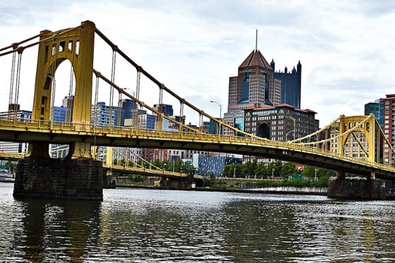 Photo of a yellow bridge in front of the Pittsburgh skyline